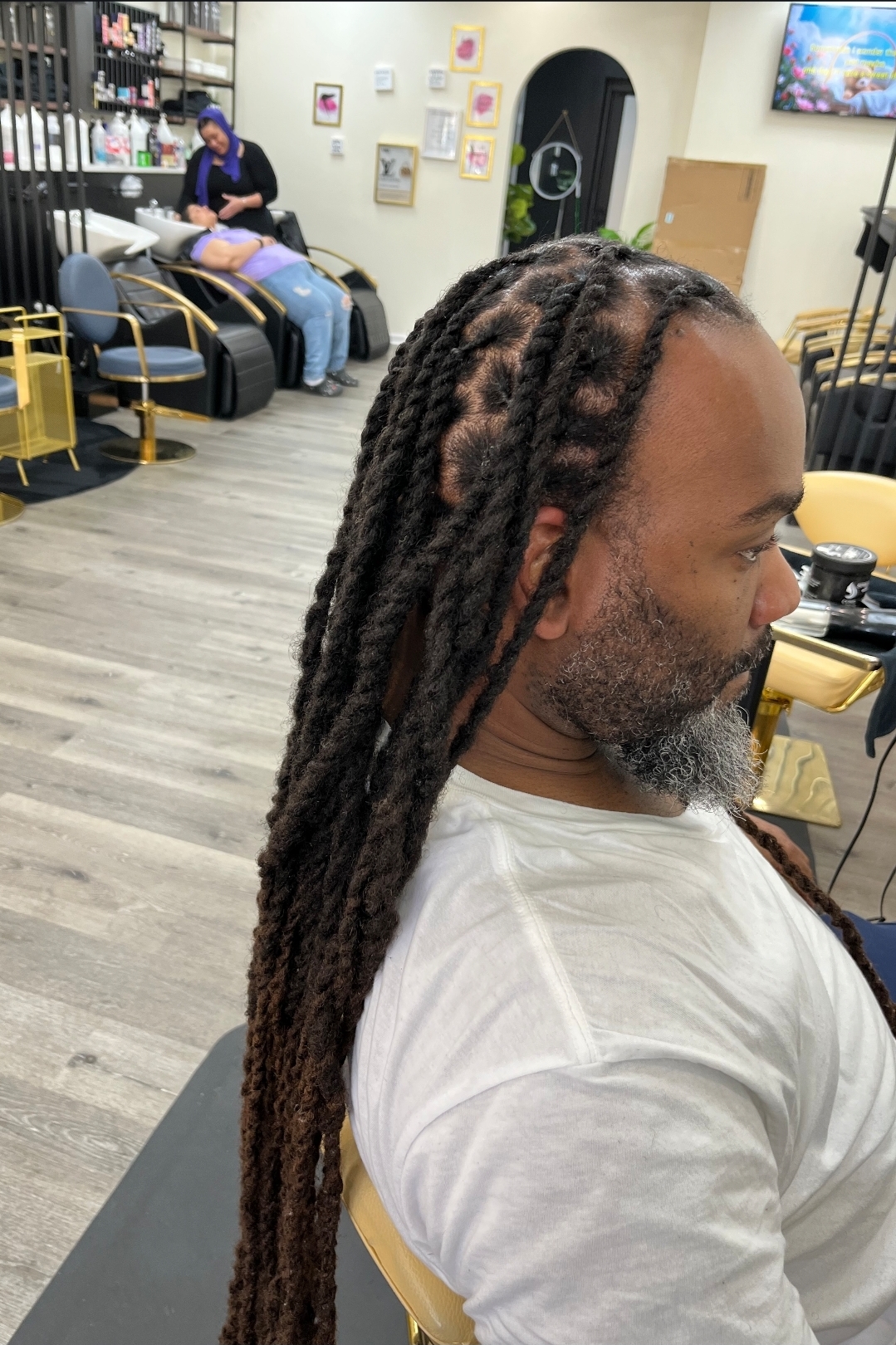 Man with long two-strand twist locs in white tee and beard — men's loc services Sinkor Beauty Salon Delaware